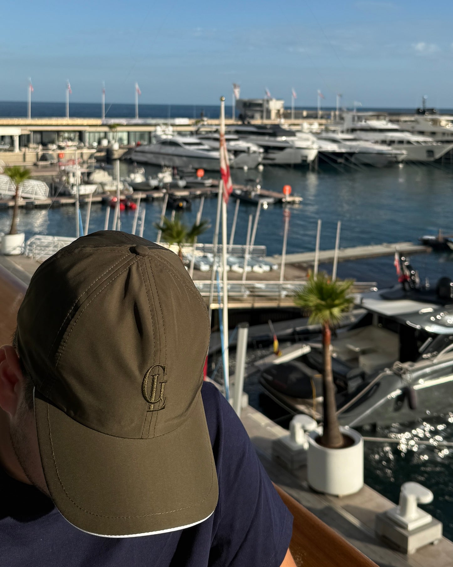 Person wearing a cap with a marina and yachts in the background